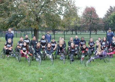 group of 20 people in racing wheelchairs on a lawn on the Illinois campus
